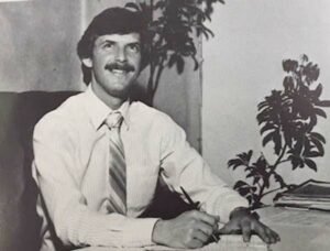 Larry Feldman writing at a desk in a black and white photo