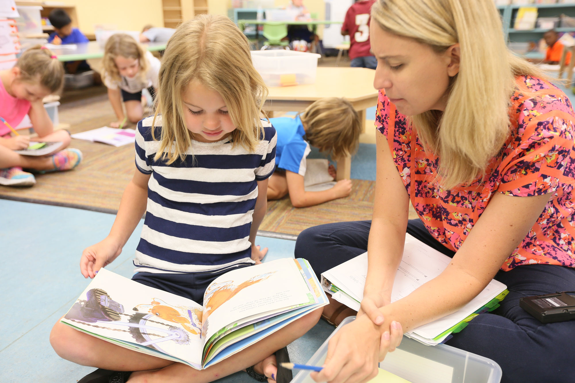 Little girl reading with a teacher.