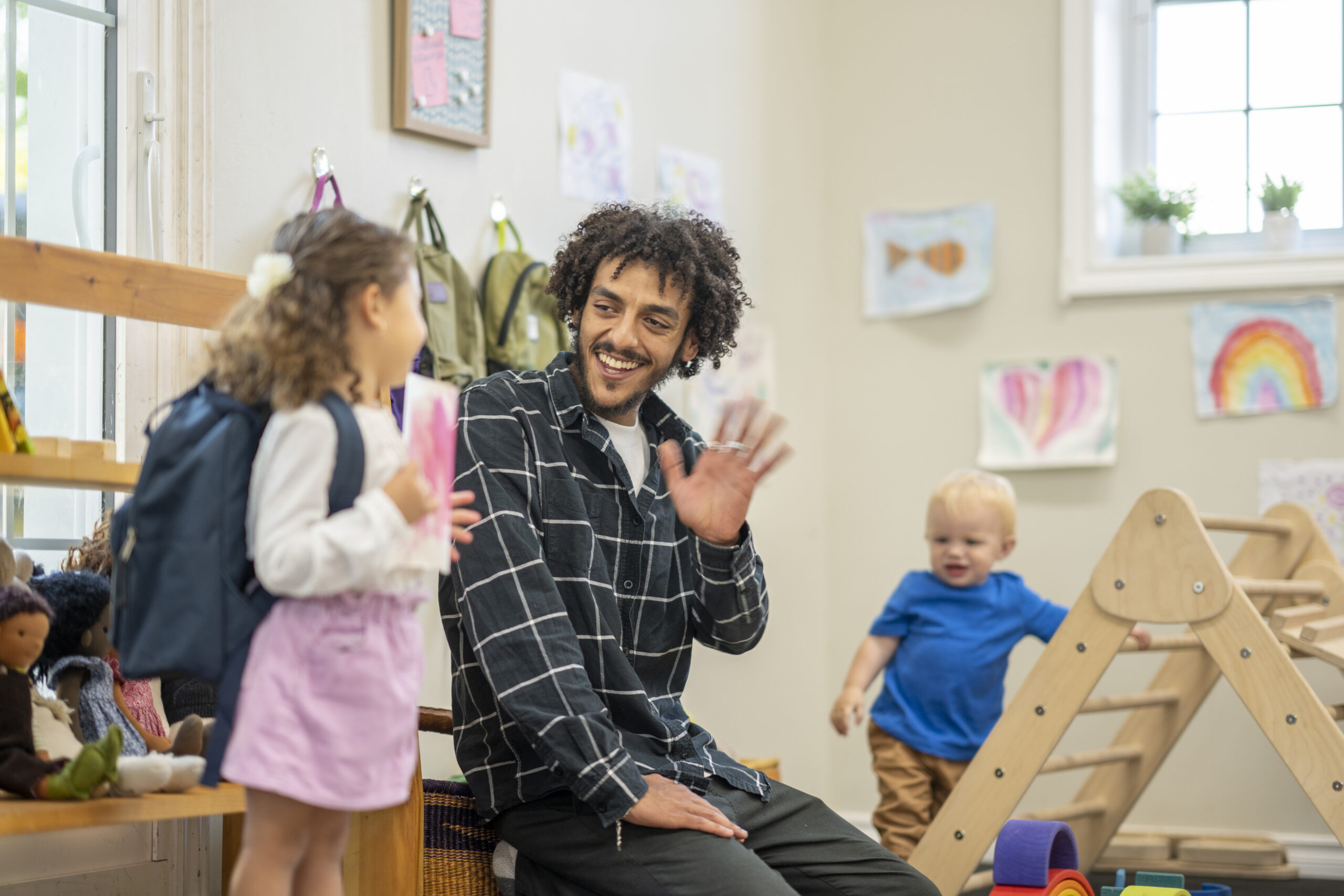 Teacher waving to early learner in the classroom