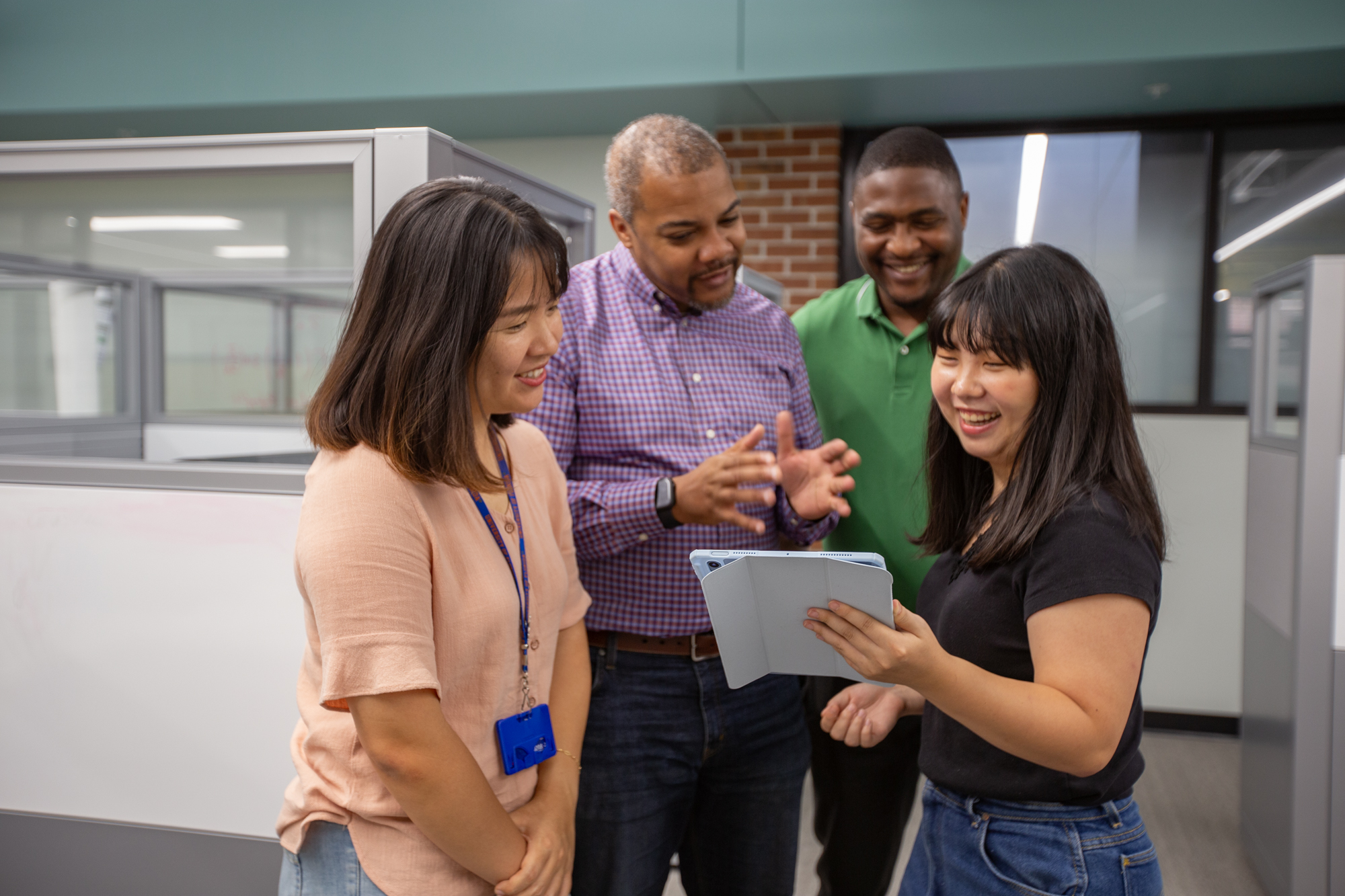 Four people looking at an iPad together and smiling.