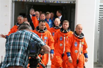 Astronauts walk out of their quarters.