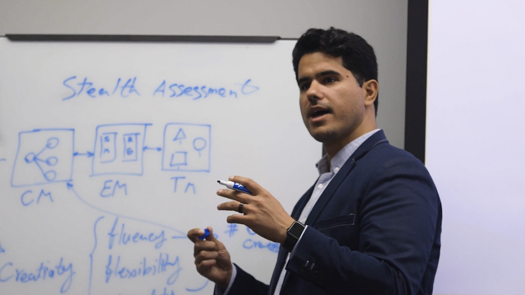 Dr. Rahimi standing in front of a white board speaking with a marker in his hand