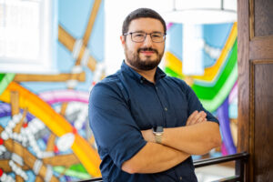 Anthony Botelho posing in front of a colorful art installation