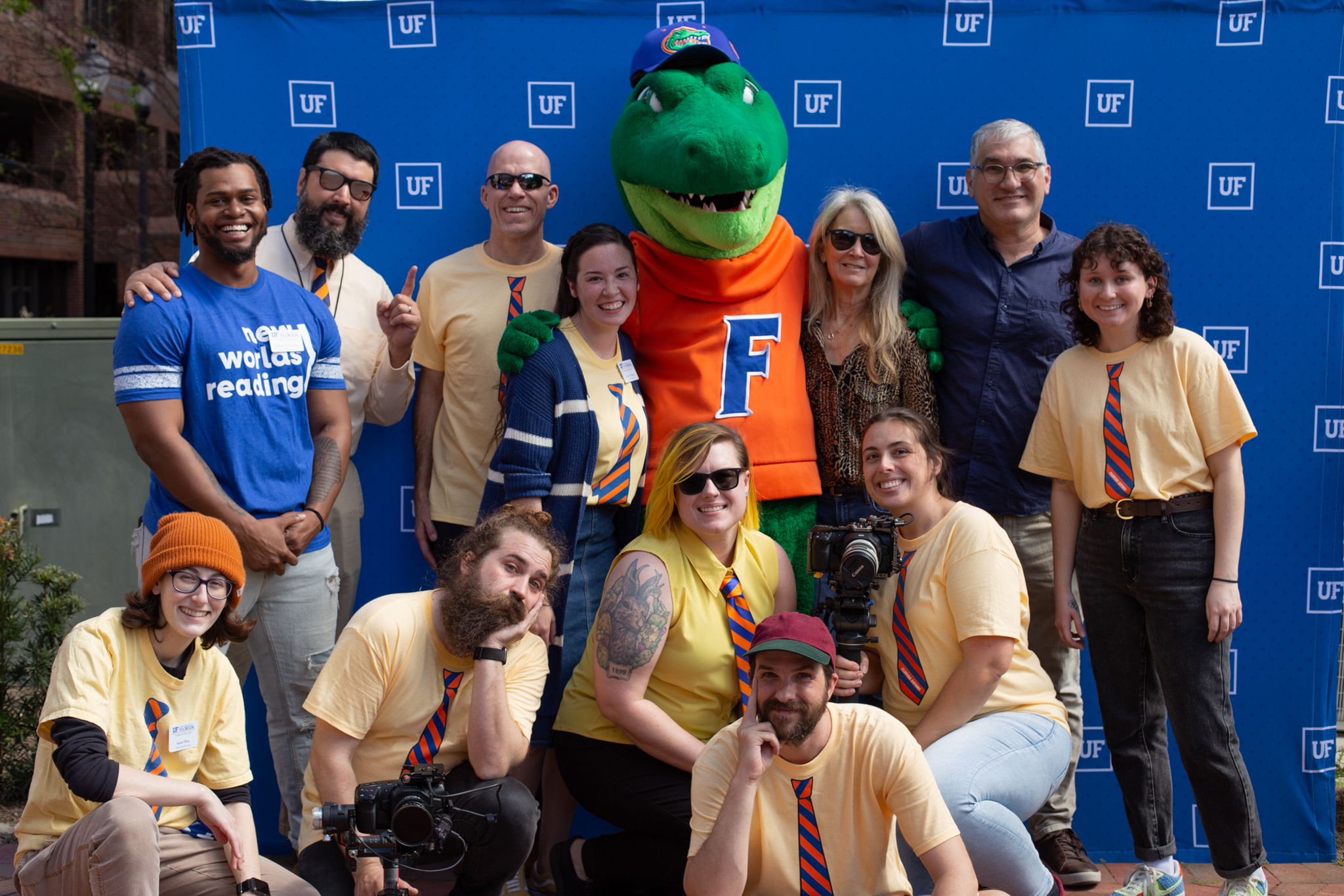 A group of people standing in front of a blue step and repeat banner and Albert, the University of Florida mascot.