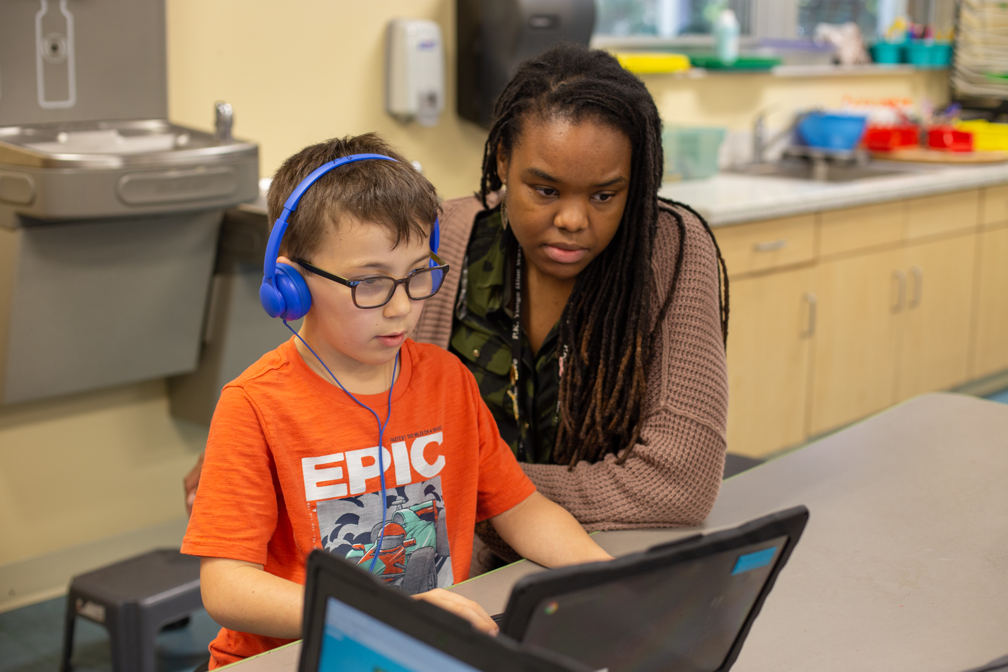 a teacher instructing a student on how to use a laptop