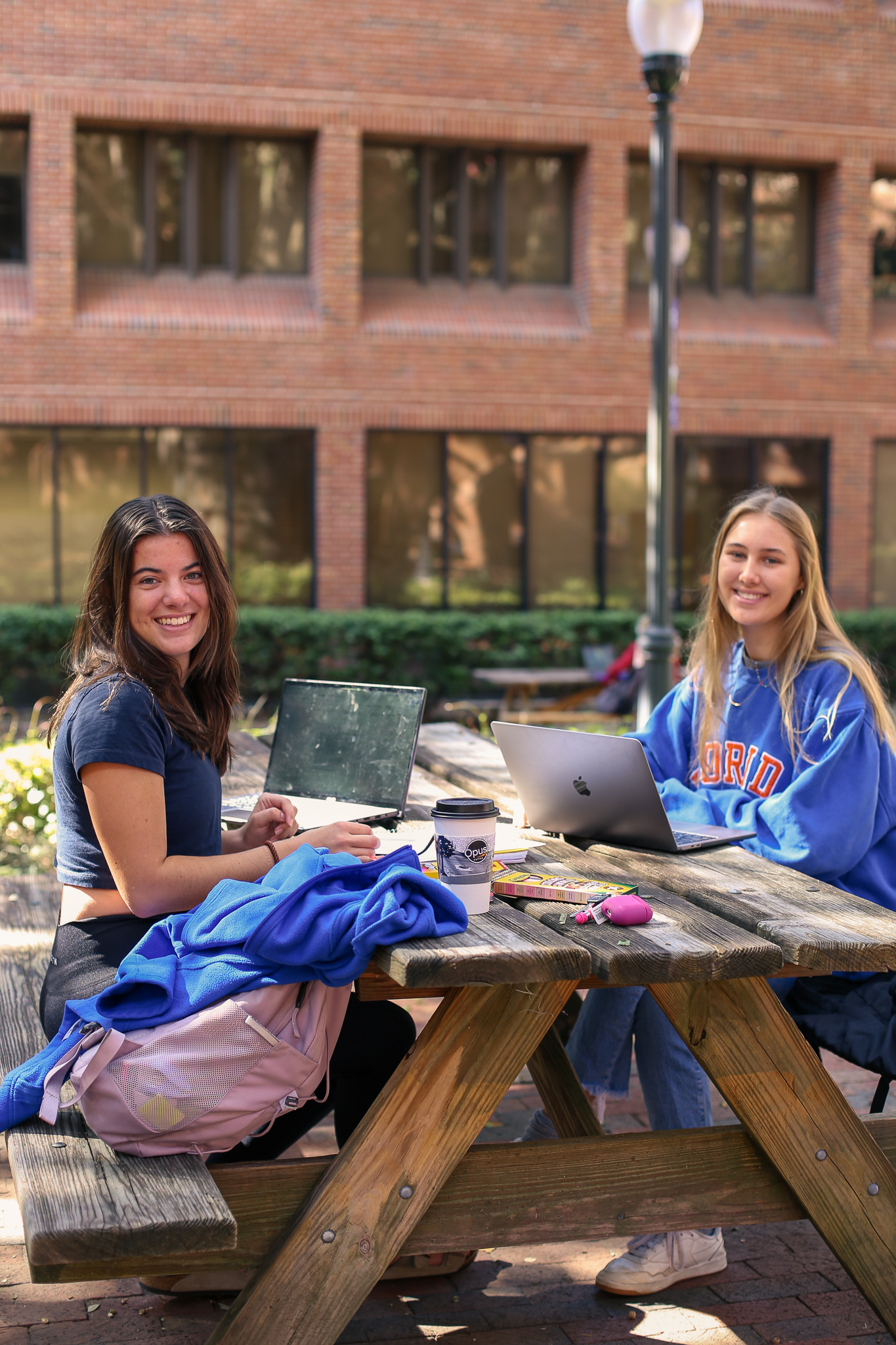 Two students sitting at a picnic table in the Norman Courtyard.